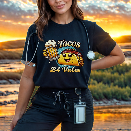 Black t-shirt featuring a fun 'Tacos B4 Vatos' design with a smiling taco character wearing a bandana and holding a beer mug. Perfect for taco lovers who prioritize food and fun with a playful style.