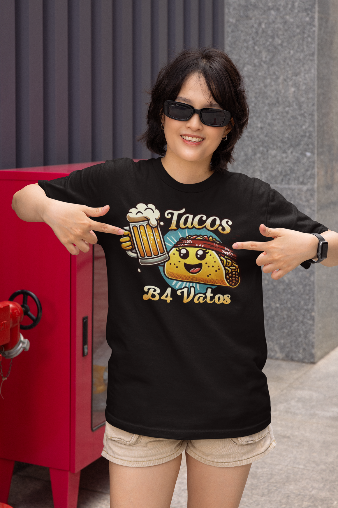 Black t-shirt featuring a fun 'Tacos B4 Vatos' design with a smiling taco character wearing a bandana and holding a beer mug. Perfect for taco lovers who prioritize food and fun with a playful style.