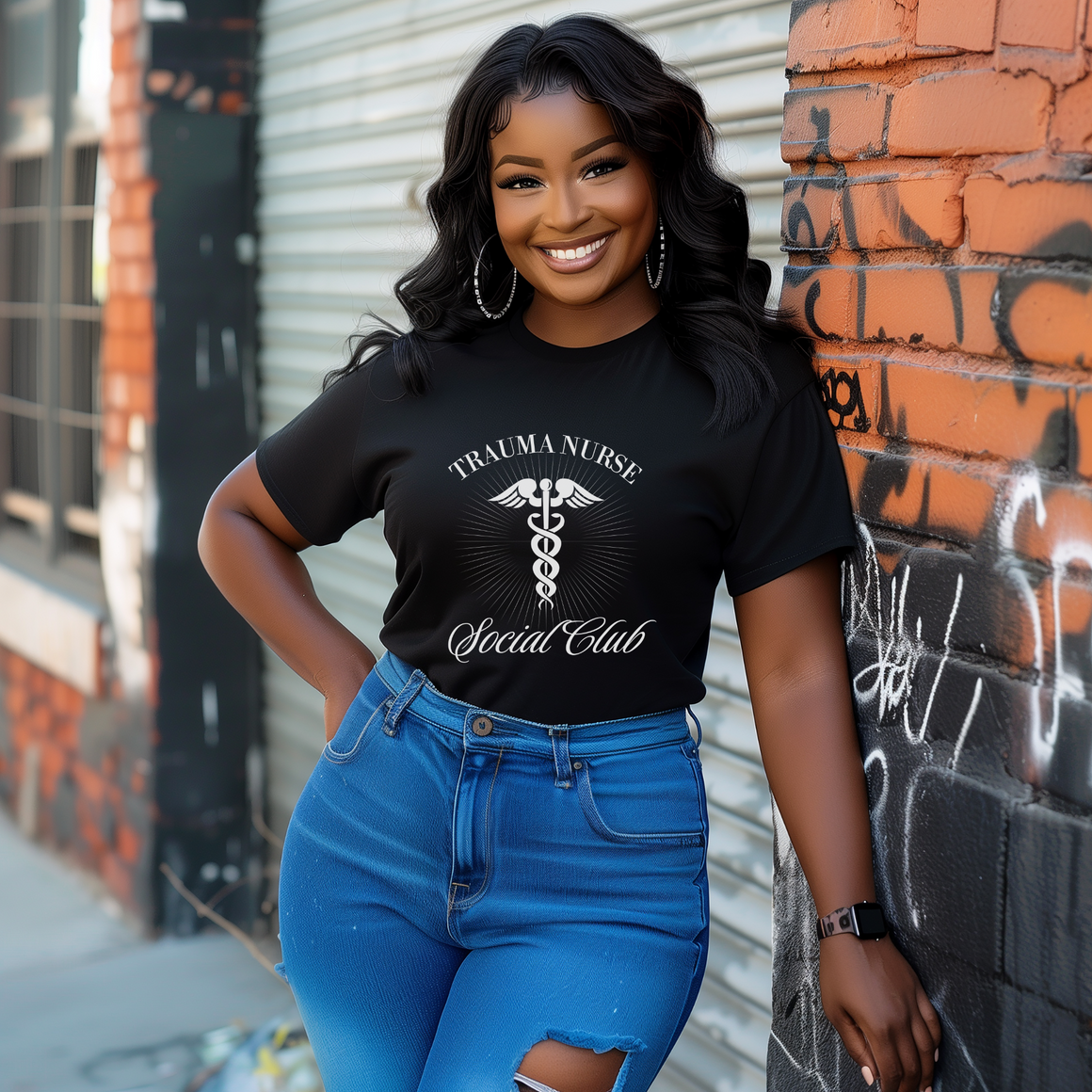 A nurse standing wearing a shirt that says Trauma Nurse Social Club and has a grapgic of a nurses caduceus