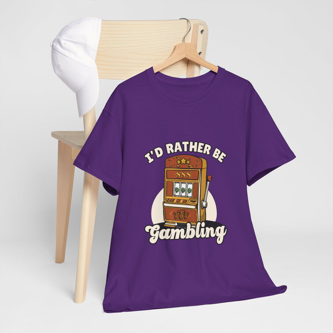 a purple t-shirt with the text "I'd Rather Be Gambling" and an illustration of a slot machine. This funny casino game shirt is perfect for anyone who loves gambling humor and casino-inspired designs