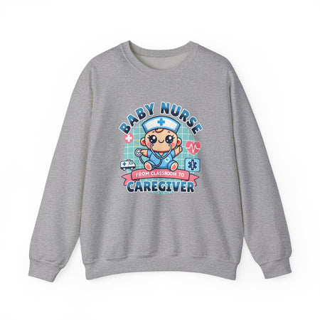 A light grey sweatshirt with a cute, cartoon-style design that reads 'Baby Nurse - From Classroom to Caregiver.' The graphic features a smiling baby nurse character in scrubs, holding a stethoscope, with icons of medical elements like an ambulance, heartbeat, and medical cross around. 