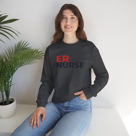 A woman smiling and wearing a charcoal ER Nurse Sweatshirt, sitting casually with a potted plant beside her.