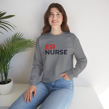 A woman smiling and wearing a dark gray ER Nurse Sweatshirt, sitting casually with a potted plant beside her.