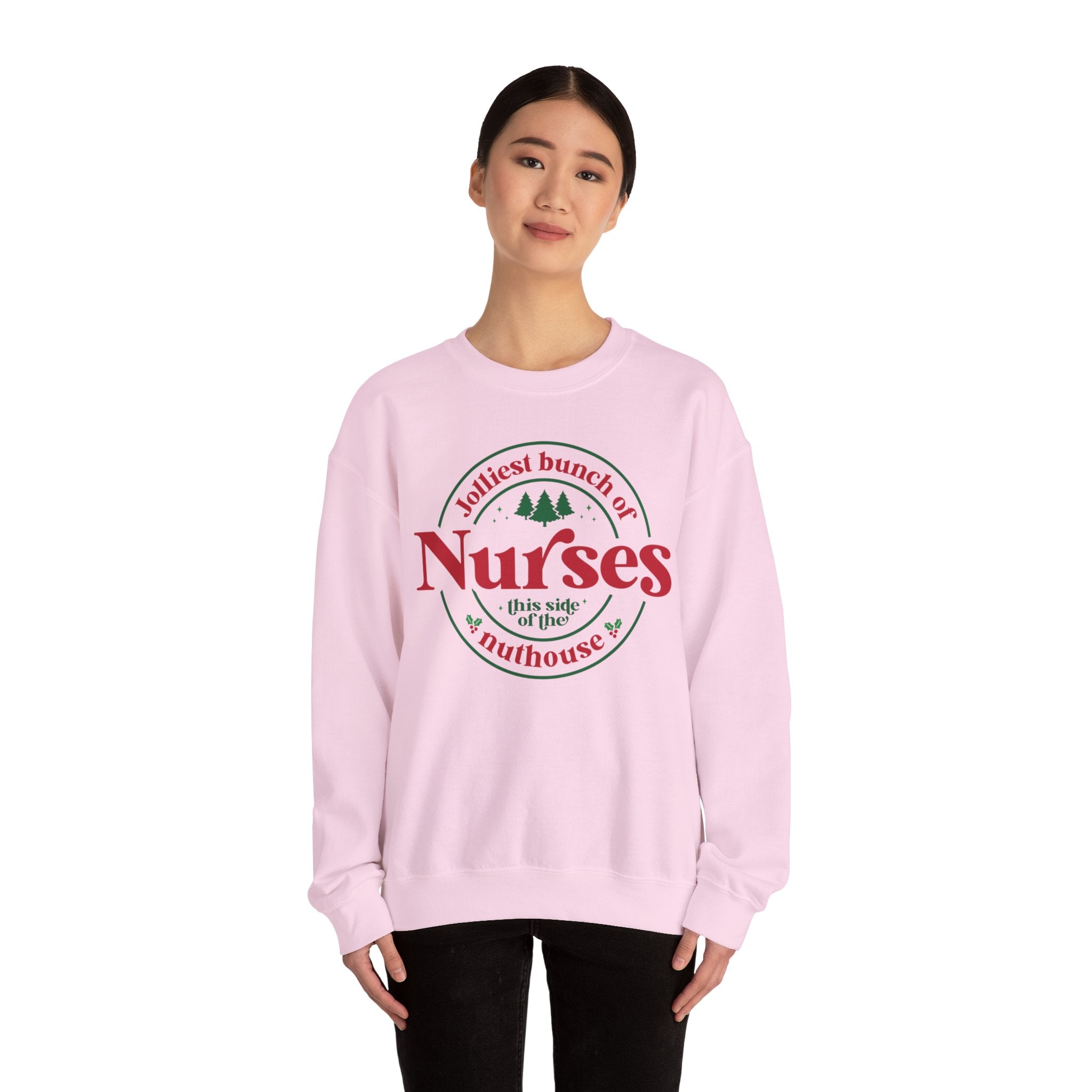 Pink Christmas sweatshirt with the humorous phrase 'Jolliest bunch of Nurses this side of the nuthouse,' surrounded by festive elements like trees and holly. A perfect holiday-themed gift for nurses with a sense of humor, celebrating Christmas in a fun and lighthearted style.