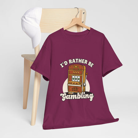  a maroon t-shirt with the text "I'd Rather Be Gambling" and an illustration of a slot machine. This funny casino game shirt is perfect for anyone who loves gambling humor and casino-inspired designs