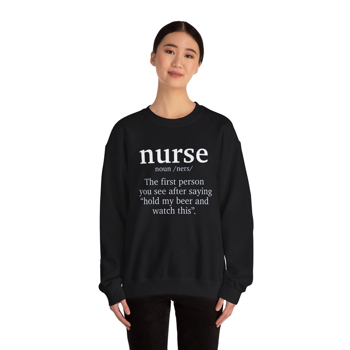 Woman wearing a black sweatshirt with the humorous text 'nurse: The first person you see after saying hold my beer and watch this.' Ideal for those looking for funny nurse-themed shirts that add a touch of humor to their wardrobe.