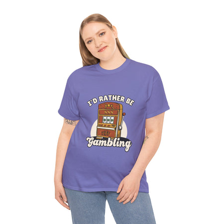 Person wearing a light purple t-shirt with the text "I'd Rather Be Gambling" and an illustration of a slot machine. This Funny Gambling themed shirts is perfect for anyone who loves gambling humor and casino-inspired designs