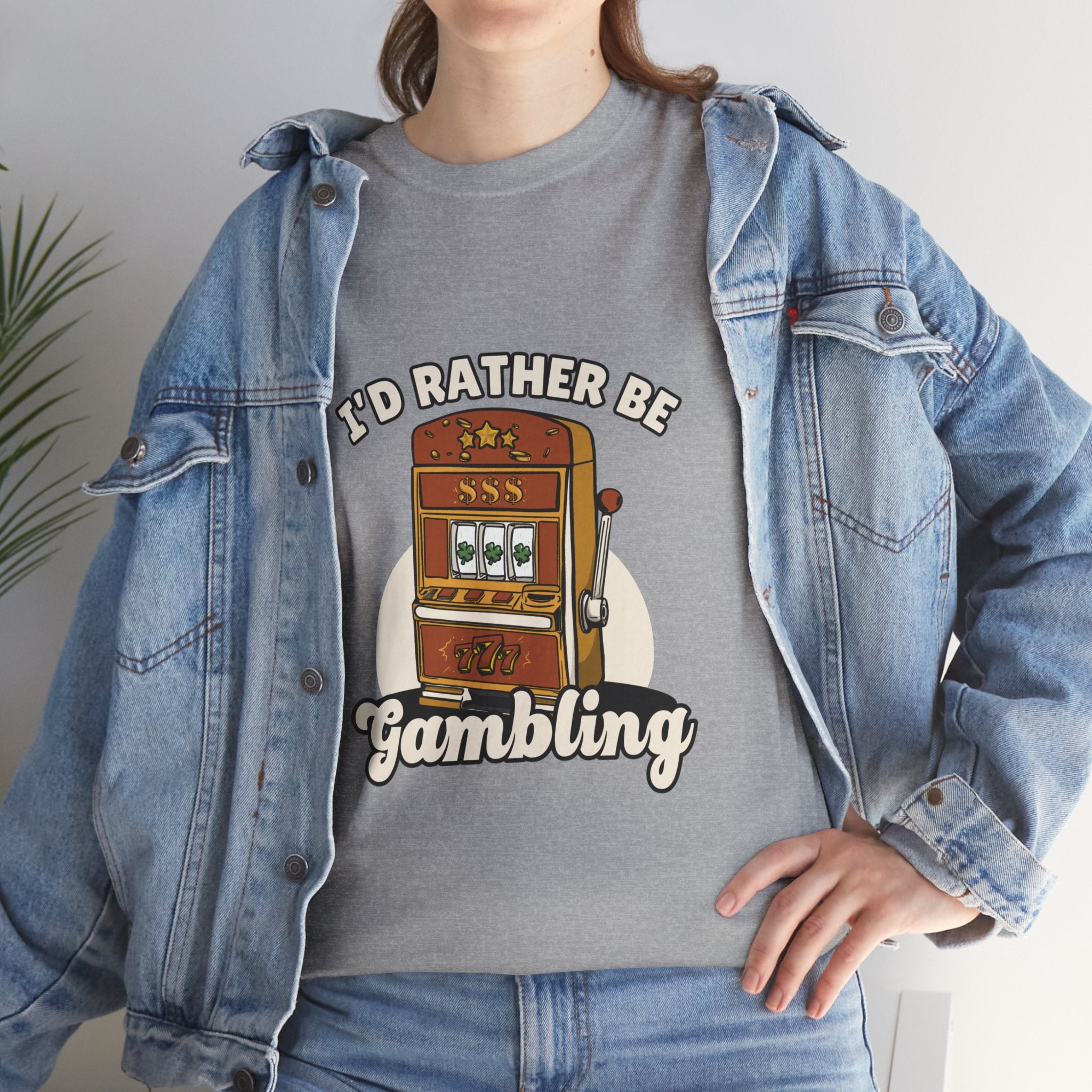 Person wearing a grey t-shirt with the text "I'd Rather Be Gambling" and an illustration of a slot machine. This funny casino game shirt is perfect for anyone who loves gambling humor and casino-inspired designs