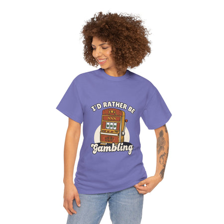 Person wearing a light purple t-shirt with the text "I'd Rather Be Gambling" and an illustration of a slot machine. This Funny Gambling themed shirts is perfect for anyone who loves gambling humor and casino-inspired designs