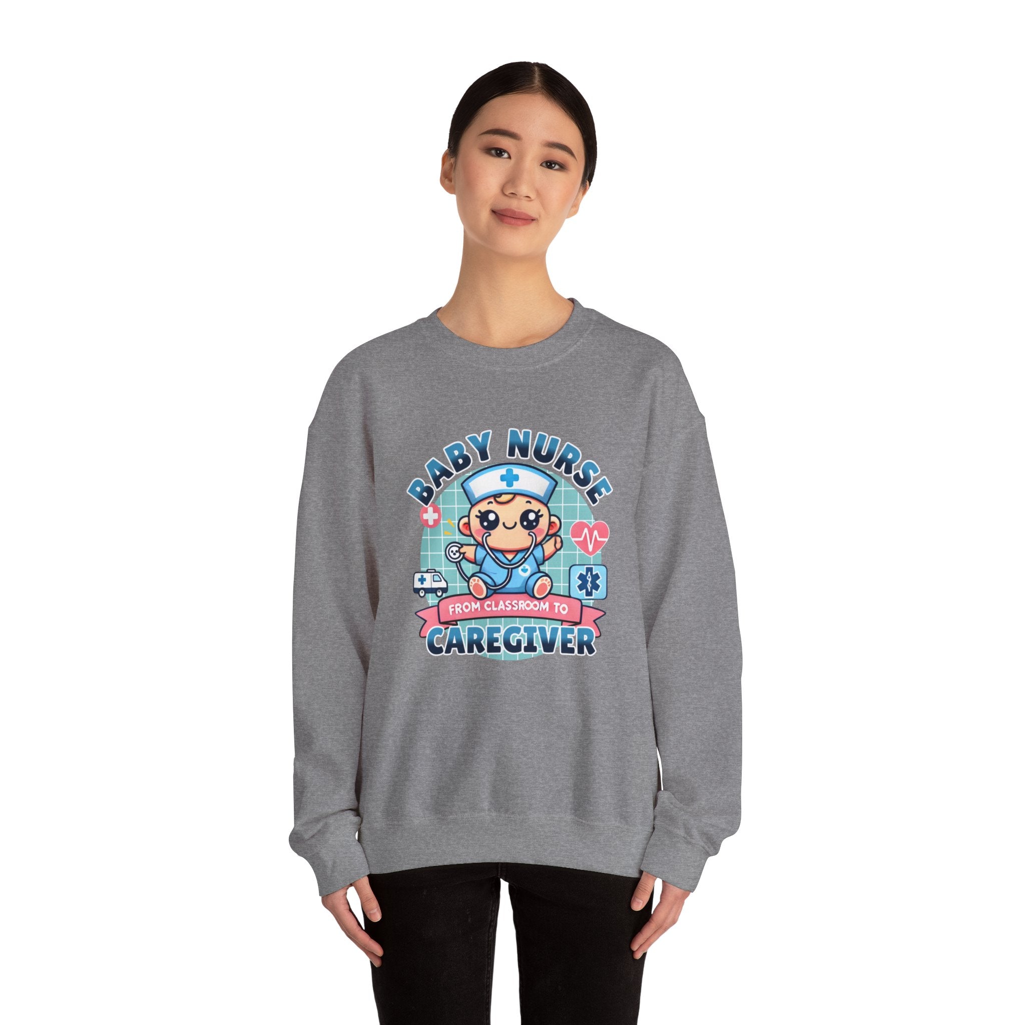 Woman wearing a Grey sweatshirt with a cute, cartoon-style design that reads 'Baby Nurse - From Classroom to Caregiver.' The graphic features a smiling baby nurse character in scrubs, holding a stethoscope, with icons of medical elements like an ambulance, heartbeat, and medical cross around. 