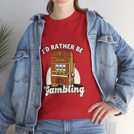 Person wearing a red t-shirt with the text "I'd Rather Be Gambling" and an illustration of a slot machine. This funny casino game shirt is perfect for anyone who loves gambling humor and casino-inspired designs