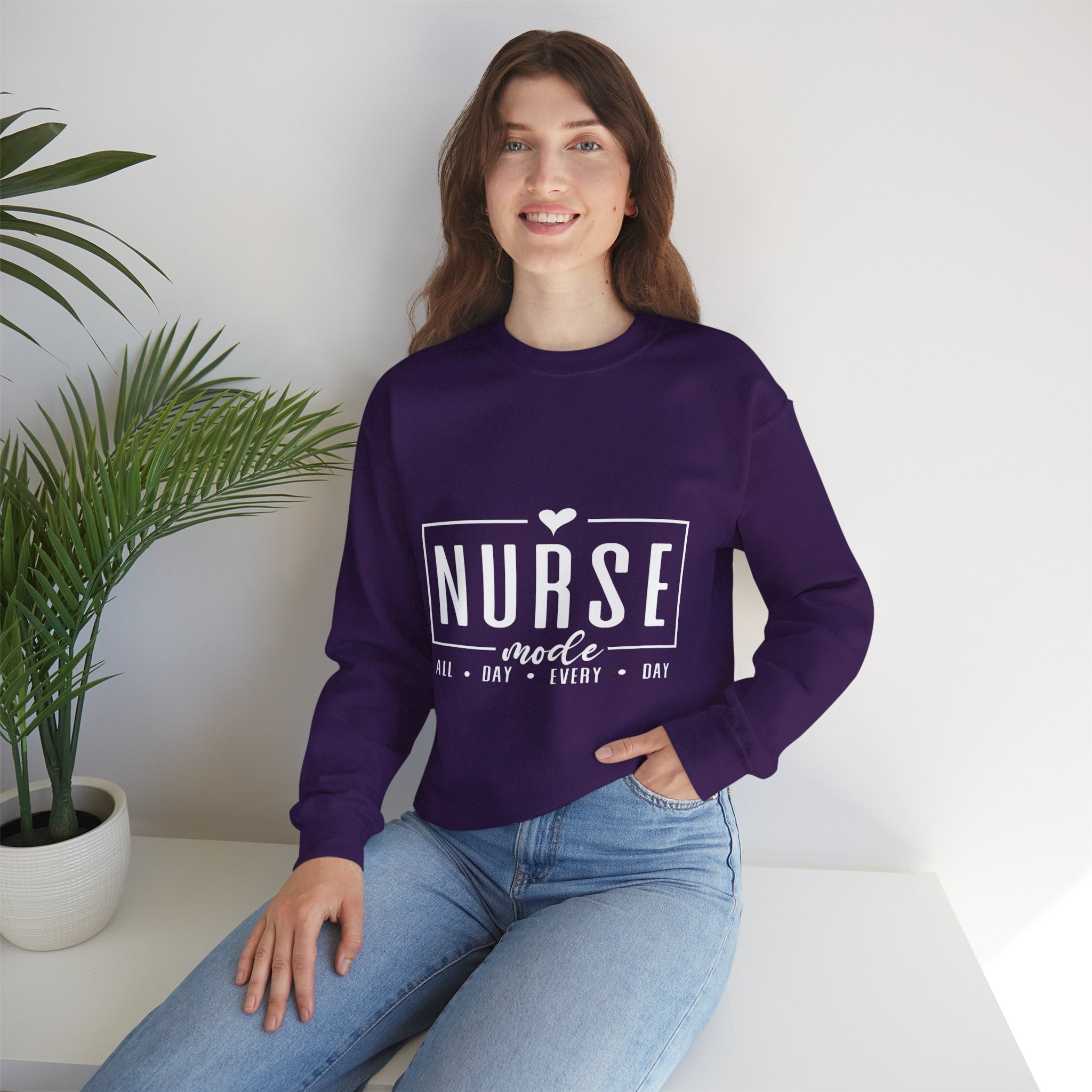 Woman wearing a purple sweatshirt with 'Nurse Mode All Day Every Day' printed in white text,  and hands on her waistband. Stylish design perfect for Nurses Week Custom Shirt Suggestions.