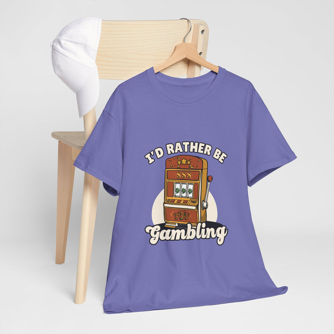  a light purple t-shirt with the text "I'd Rather Be Gambling" and an illustration of a slot machine. This Funny Gambling themed shirts is perfect for anyone who loves gambling humor and casino-inspired designs