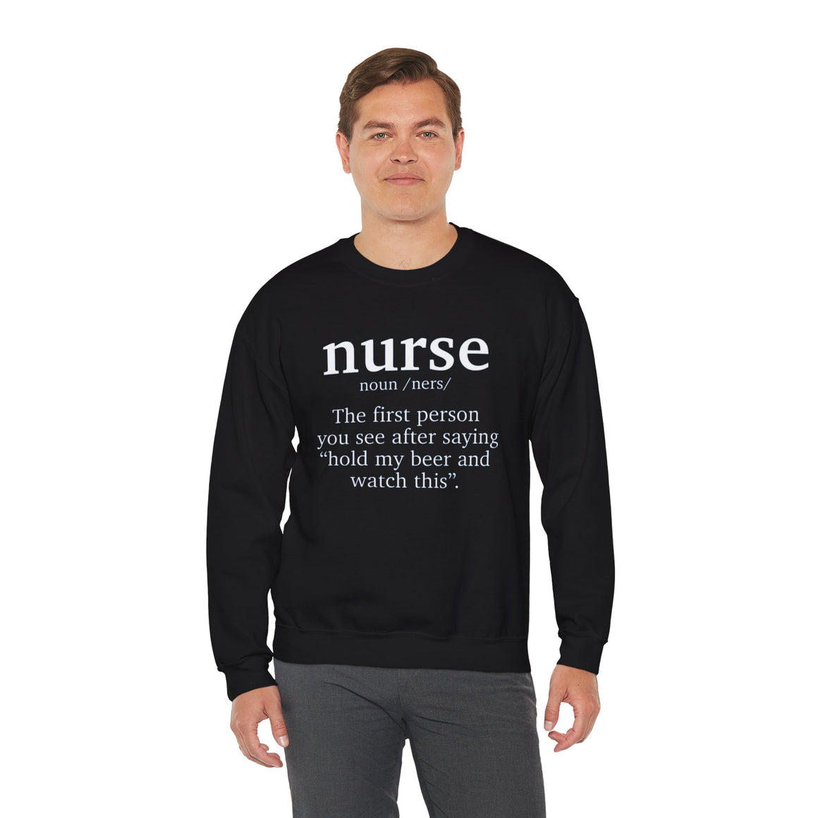 Man wearing a black sweatshirt with the humorous text 'nurse: The first person you see after saying hold my beer and watch this.' Ideal for those looking for funny nurse-themed shirts that add a touch of humor to their wardrobe.