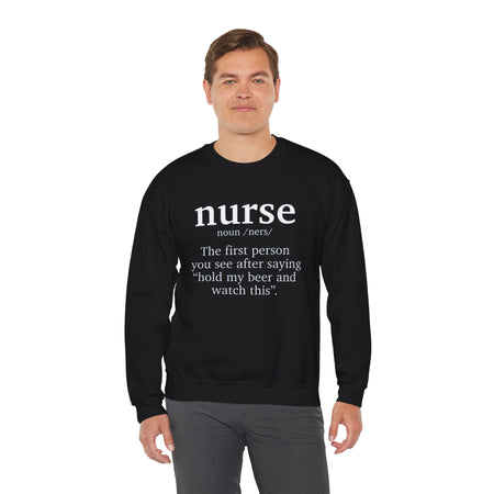 Man wearing a black sweatshirt with the humorous text 'nurse: The first person you see after saying hold my beer and watch this.' Ideal for those looking for funny nurse-themed shirts that add a touch of humor to their wardrobe.