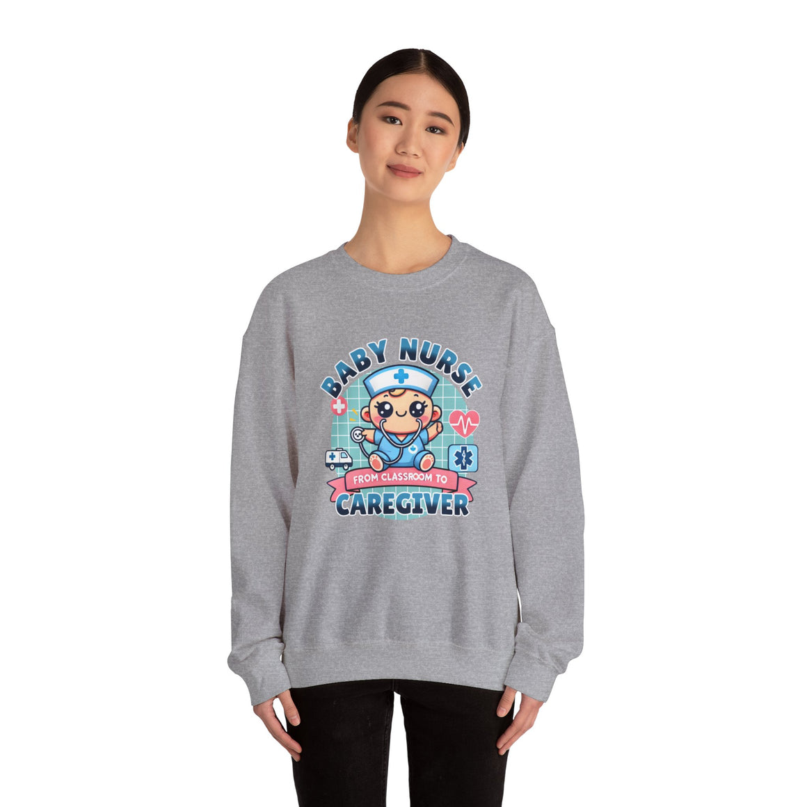 Woman wearing a Slate Grey sweatshirt with a cute, cartoon-style design that reads 'Baby Nurse - From Classroom to Caregiver.' The graphic features a smiling baby nurse character in scrubs, holding a stethoscope, with icons of medical elements like an ambulance, heartbeat, and medical cross around. 