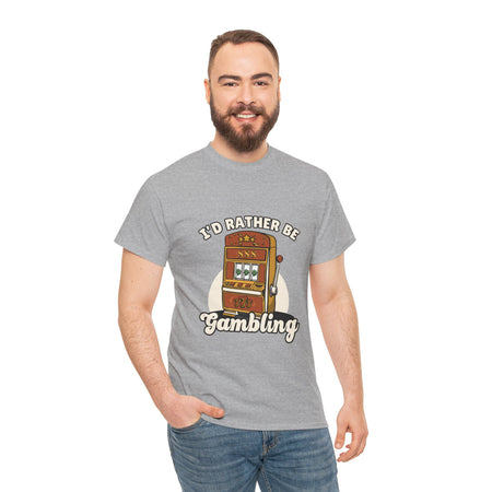 Person wearing a grey t-shirt with the text "I'd Rather Be Gambling" and an illustration of a slot machine. This funny casino game shirt is perfect for anyone who loves gambling humor and casino-inspired designs