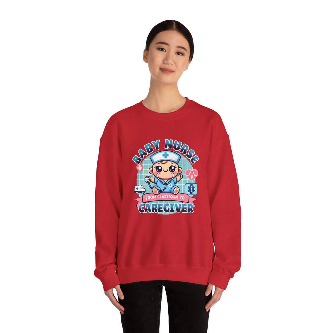 Woman wearing a Red sweatshirt with a cute, cartoon-style design that reads 'Baby Nurse - From Classroom to Caregiver.' The graphic features a smiling baby nurse character in scrubs, holding a stethoscope, with icons of medical elements like an ambulance, heartbeat, and medical cross around. 