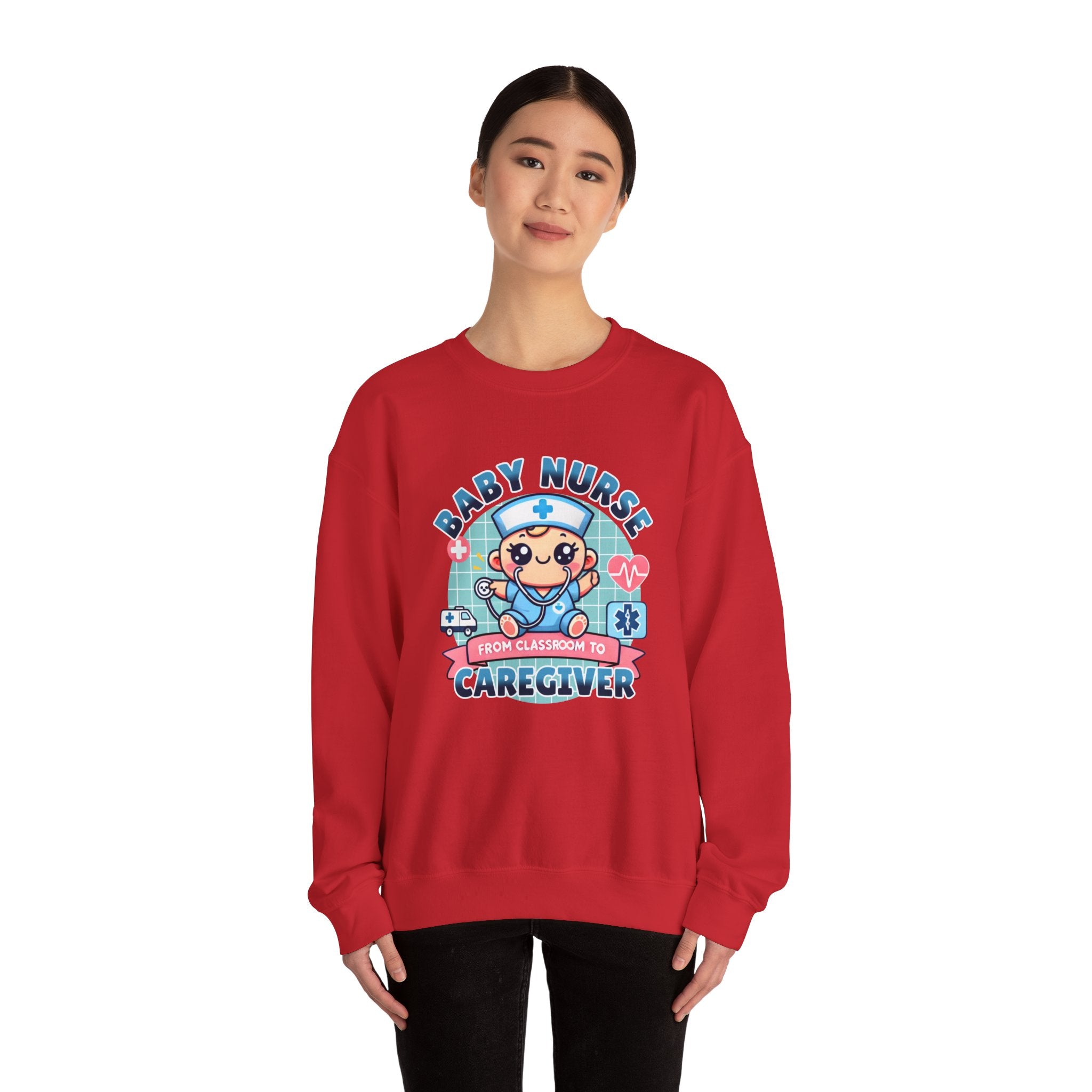 Woman wearing a Red sweatshirt with a cute, cartoon-style design that reads 'Baby Nurse - From Classroom to Caregiver.' The graphic features a smiling baby nurse character in scrubs, holding a stethoscope, with icons of medical elements like an ambulance, heartbeat, and medical cross around. 