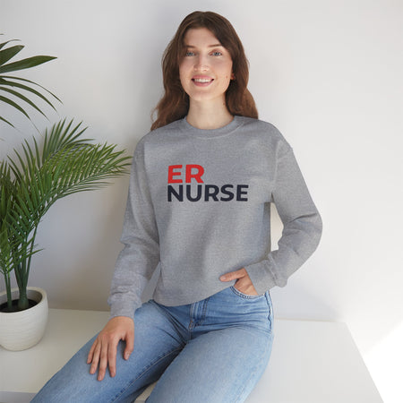 A woman smiling and wearing a light gray ER Nurse Sweatshirt, sitting casually with a potted plant beside her.