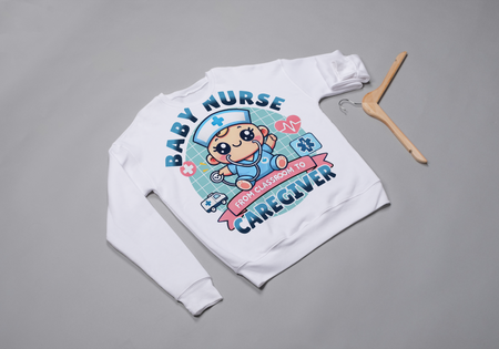 A white sweatshirt with a cute, cartoon-style design that reads 'Baby Nurse - From Classroom to Caregiver.' The graphic features a smiling baby nurse character in scrubs, holding a stethoscope, with icons of medical elements like an ambulance, heartbeat, and medical cross around. 