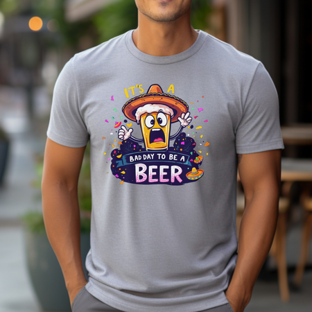 Man wearing a gray Fiesta San Antonio T-shirt featuring a cartoon beer character in a sombrero, surrounded by colorful confetti. The text reads 'It's a bad day to be a beer.