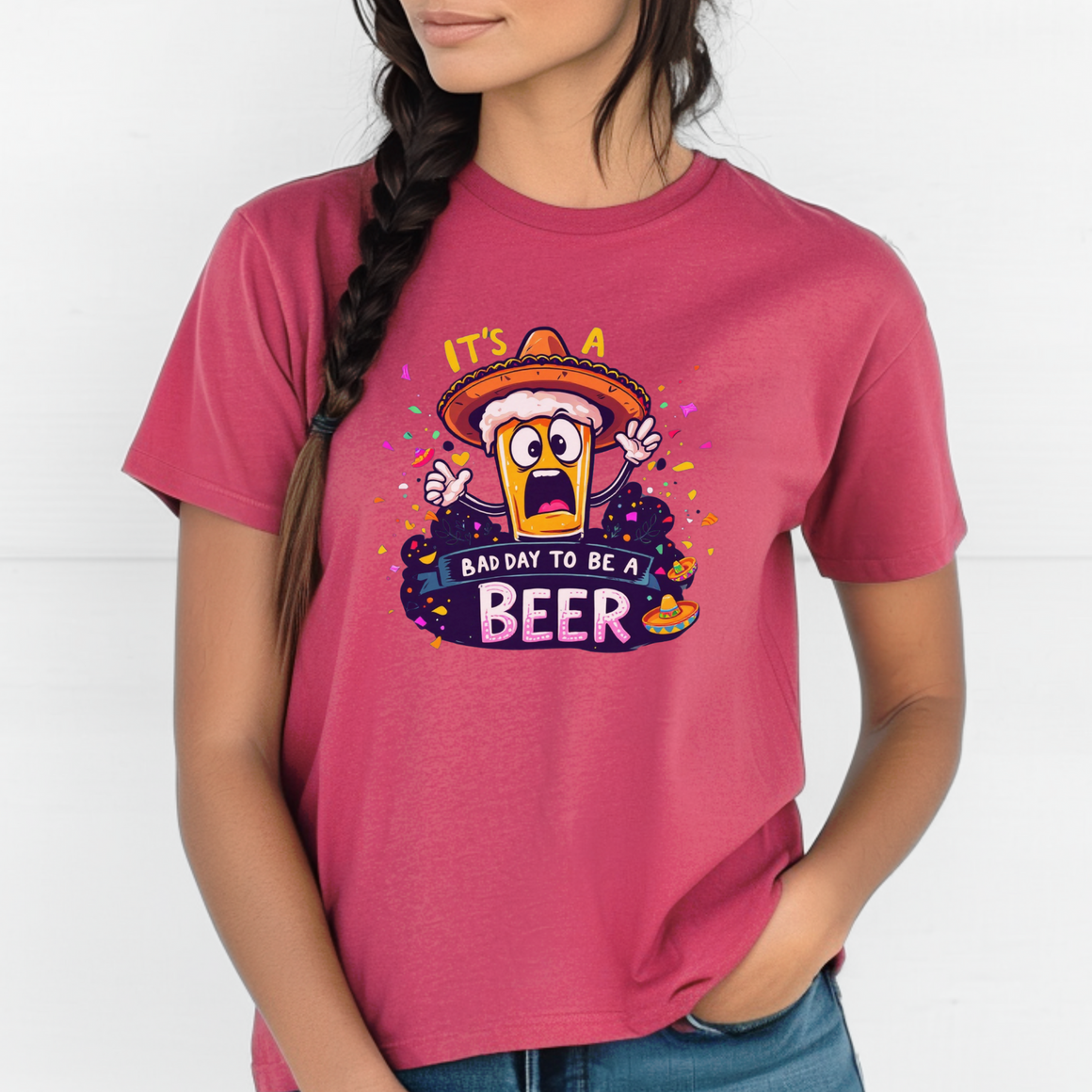Woman wearing a pink T-shirt featuring a cartoon beer character in a sombrero, surrounded by colorful confetti. The text reads 'It's a bad day to be a beer
