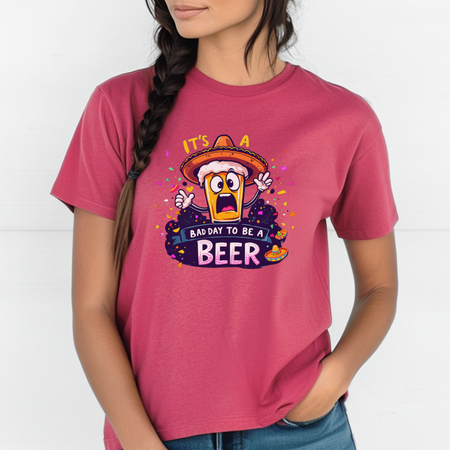 Woman wearing a pink T-shirt featuring a cartoon beer character in a sombrero, surrounded by colorful confetti. The text reads 'It's a bad day to be a beer