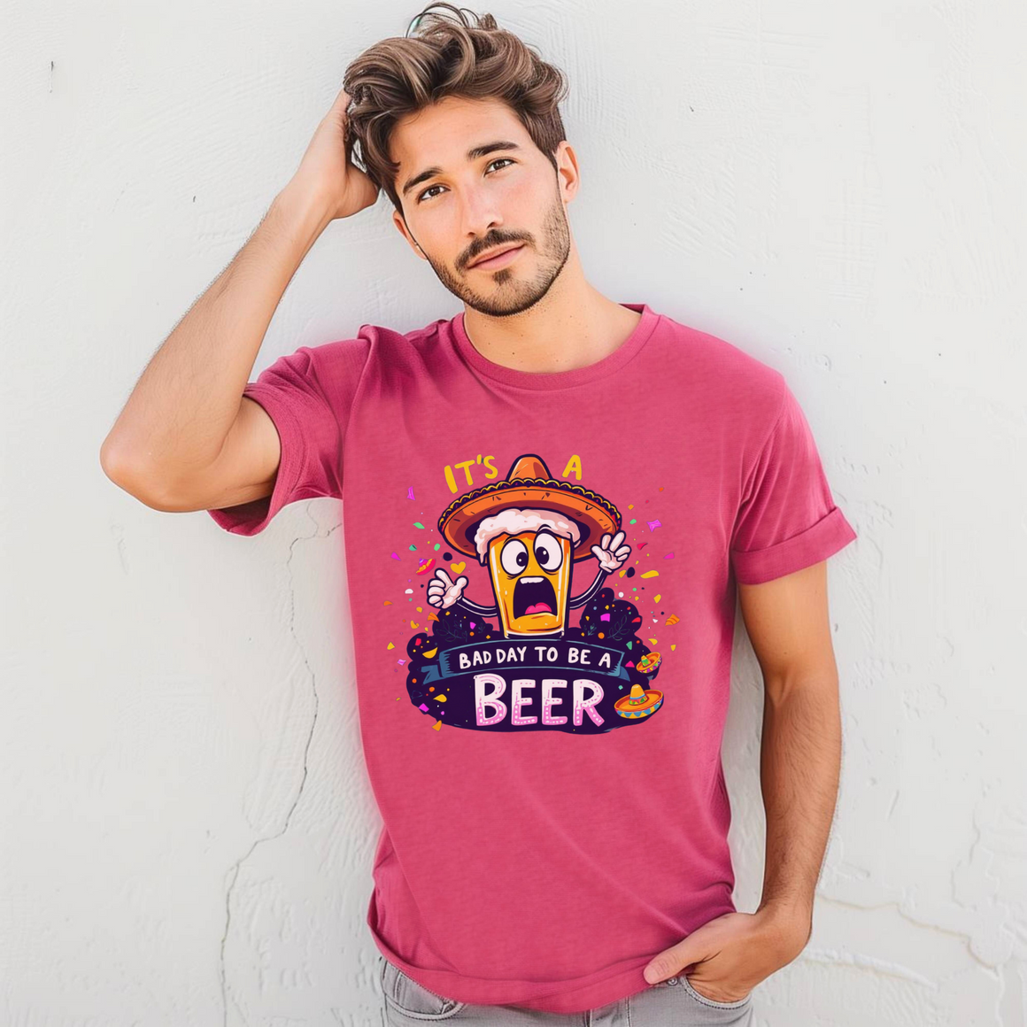 Man wearing a pink Fiesta San Antonio T-shirt featuring a cartoon beer character in a sombrero, surrounded by colorful confetti. The text reads 'It's a bad day to be a beer.