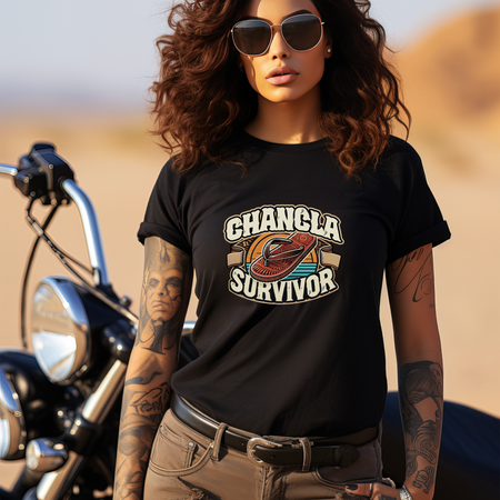 Funny Mexican t-shirt featuring the phrase 'Chancla Survivor.' Woman wearing sunglasses and standing by a motorcycle, embodying a bold and resilient vibe. Perfect for those who understand the humor behind the 'chancla' discipline with a retro style and desert background.