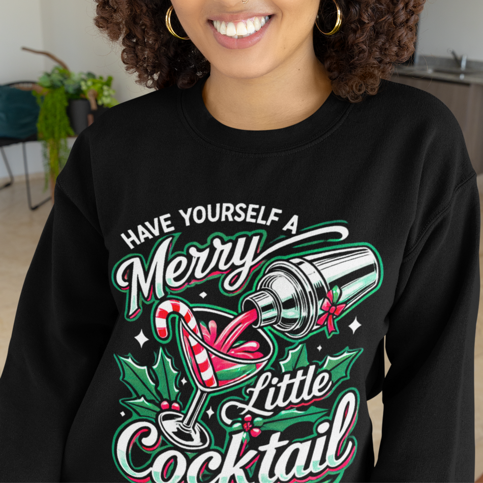 Black Christmas sweatshirt featuring a festive cocktail graphic with candy canes, holly leaves, and the playful text 'Have Yourself a Merry Little Cocktail.' Ideal holiday apparel for cocktail lovers looking to celebrate the season with a fun and stylish Christmas-themed sweatshirt.