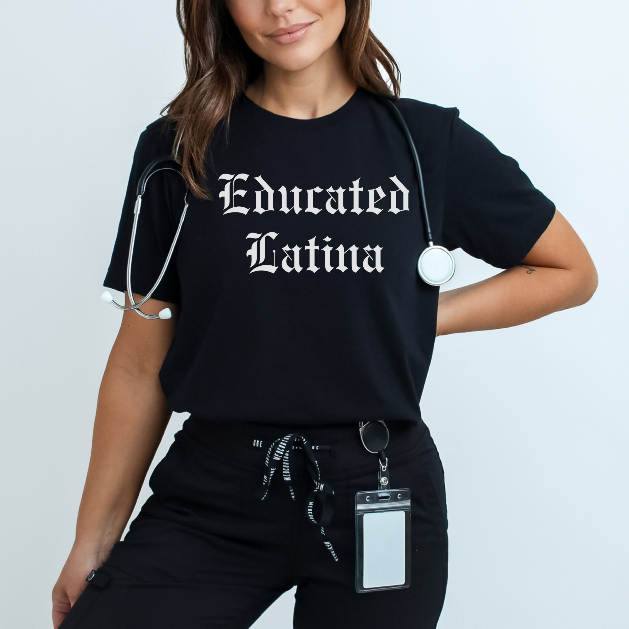 Female healthcare professional wearing a black t-shirt with 'Educated Latina' in bold, old English lettering. This shirt embodies educated Latina T-shirt sayings and quotes, celebrating Latinx pride and identity with style and empowerment. Perfect for showcasing cultural heritage in a professional yet bold look.