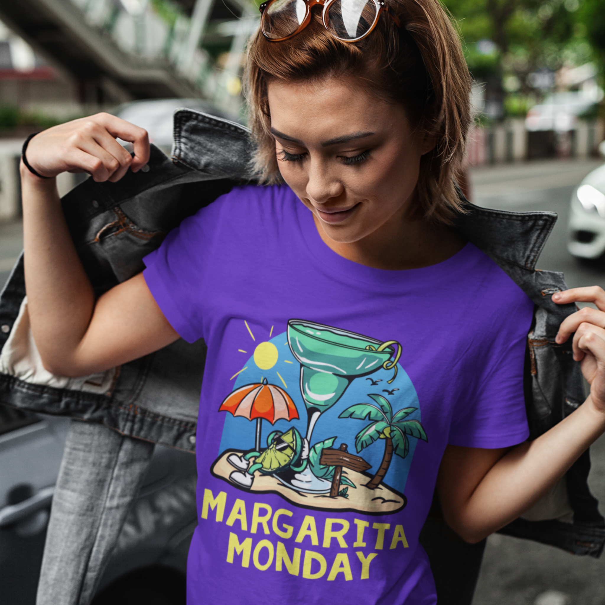 A woman wearing a purple t-shirt with a fun "Margarita Monday" design, showcasing tropical vibes with a large margarita glass, palm trees, and a beach scene. 