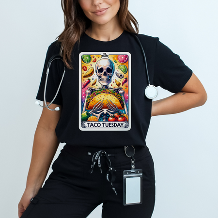 Black t-shirt with a unique 'Taco Tuesday' design featuring a skeleton holding a large taco, surrounded by vibrant ingredients like lime slices, chili peppers, and tomatoes. Perfect for those who enjoy a fun, slightly edgy take on Taco Tuesday.