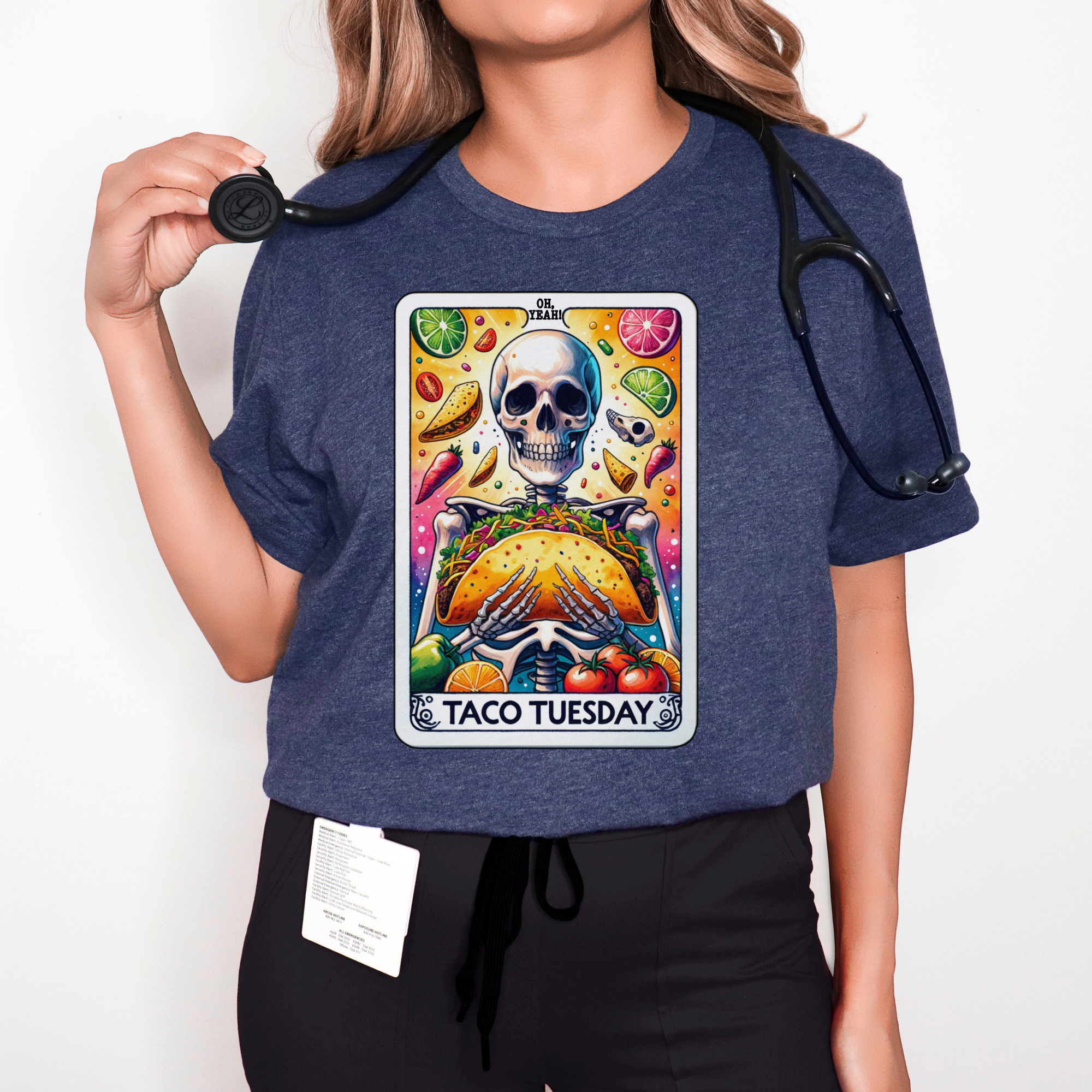 T-shirt with a unique 'Taco Tuesday' design featuring a skeleton holding a large taco, surrounded by vibrant ingredients like lime slices, chili peppers, and tomatoes. Perfect for those who enjoy a fun, slightly edgy take on Taco Tuesday.