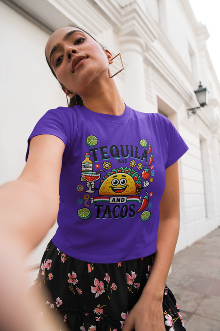 Purple t-shirt featuring a festive 'Tequila and Tacos' design with a smiling taco character, tequila bottle, margarita glass, lime slices, and chili peppers. Perfect for celebrating fiestas and taco nights with a fun and lively style.